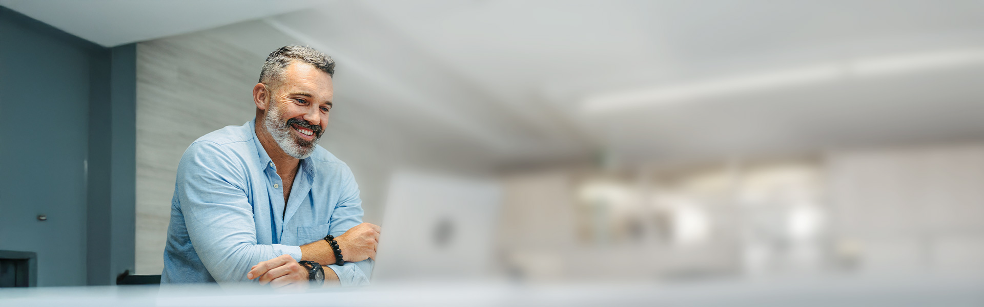 ein Mann in einem blauen Hemd lächelt und schaut auf die Kamera